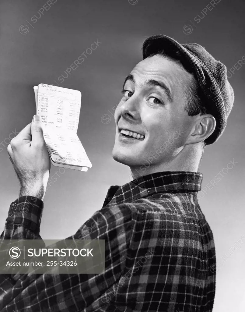 Vintage Photograph. Man in wool cap holding up bank receipt and smiling