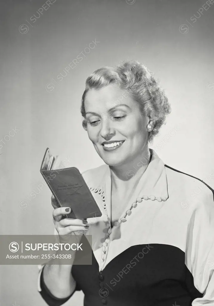 Vintage photograph. Woman in collared blouse smiling and reading book