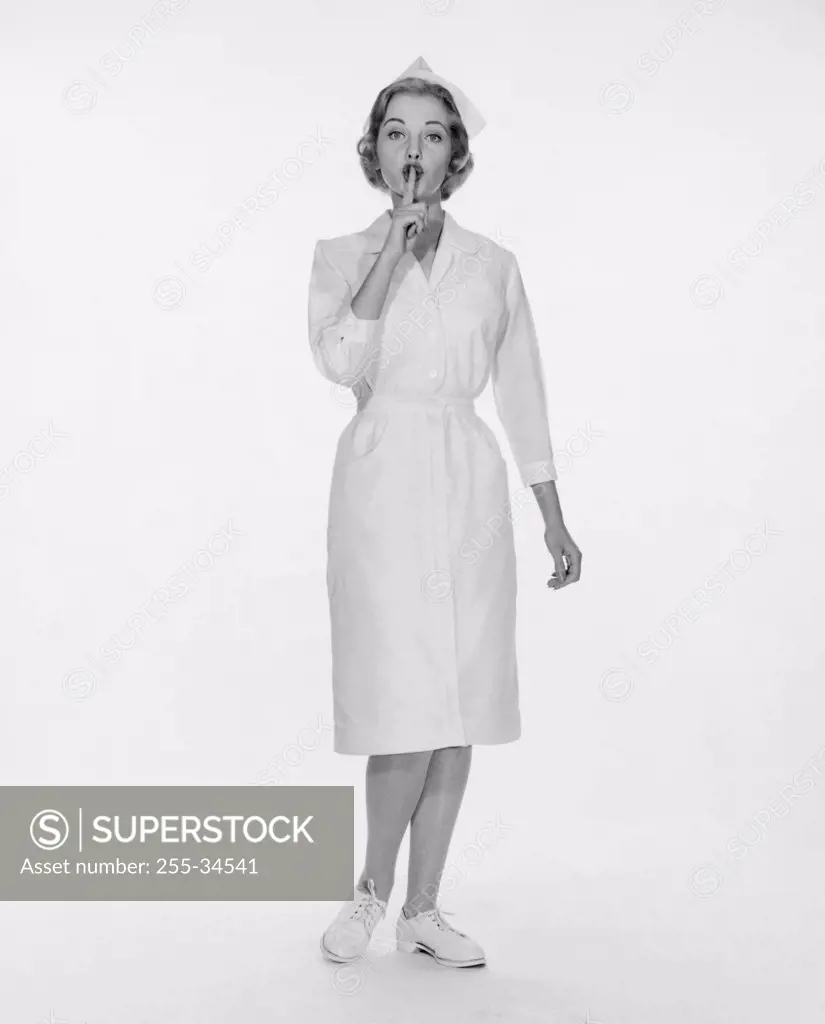 Portrait of a female nurse standing with her finger on her lips