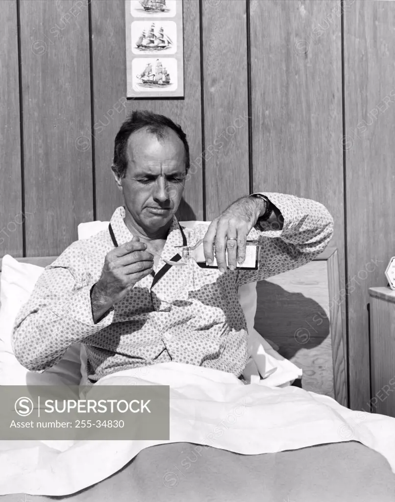 Mature man in bed pouring medicine into a spoon
