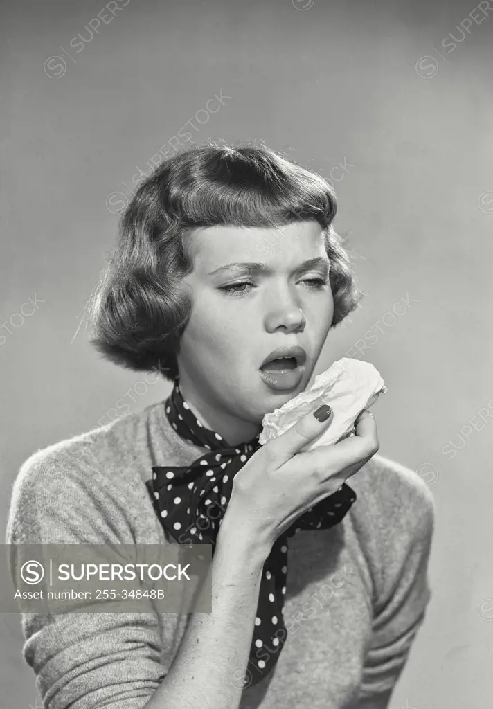 Vintage photograph. Woman with short bangs sneezing into tissue
