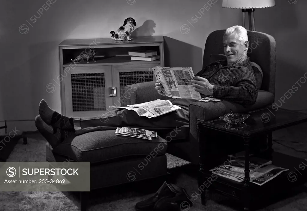Man relaxing in chair reading newspaper