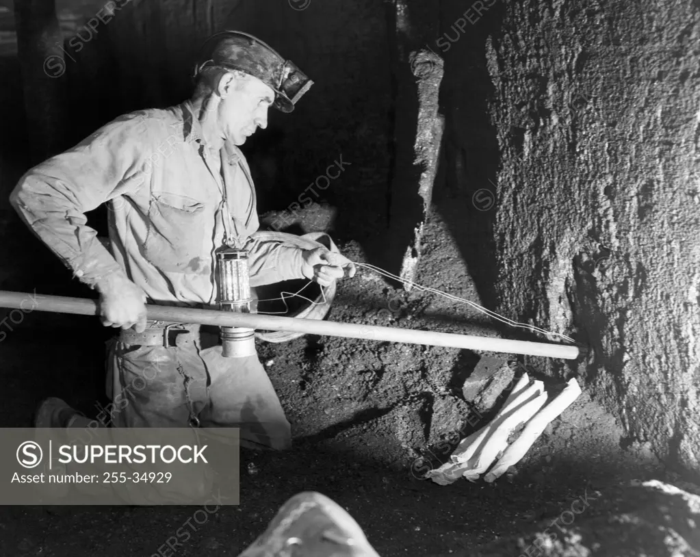 Side profile of a coal miner putting dynamite in to a hole