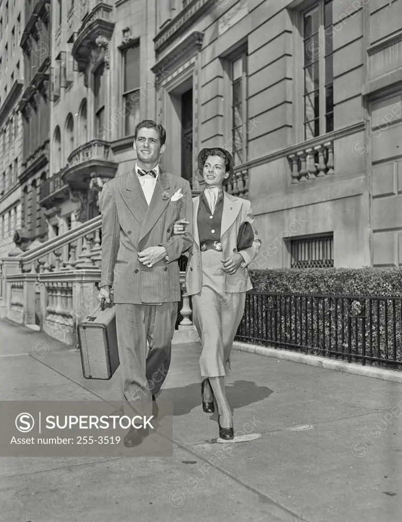 Vintage photograph. Man and wife walking down street with arms locked holding briefcase