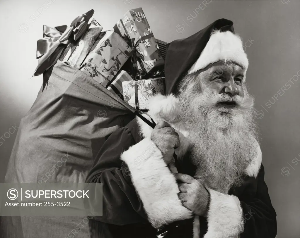 Side profile of Santa Claus carrying a sack of Christmas presents on his back