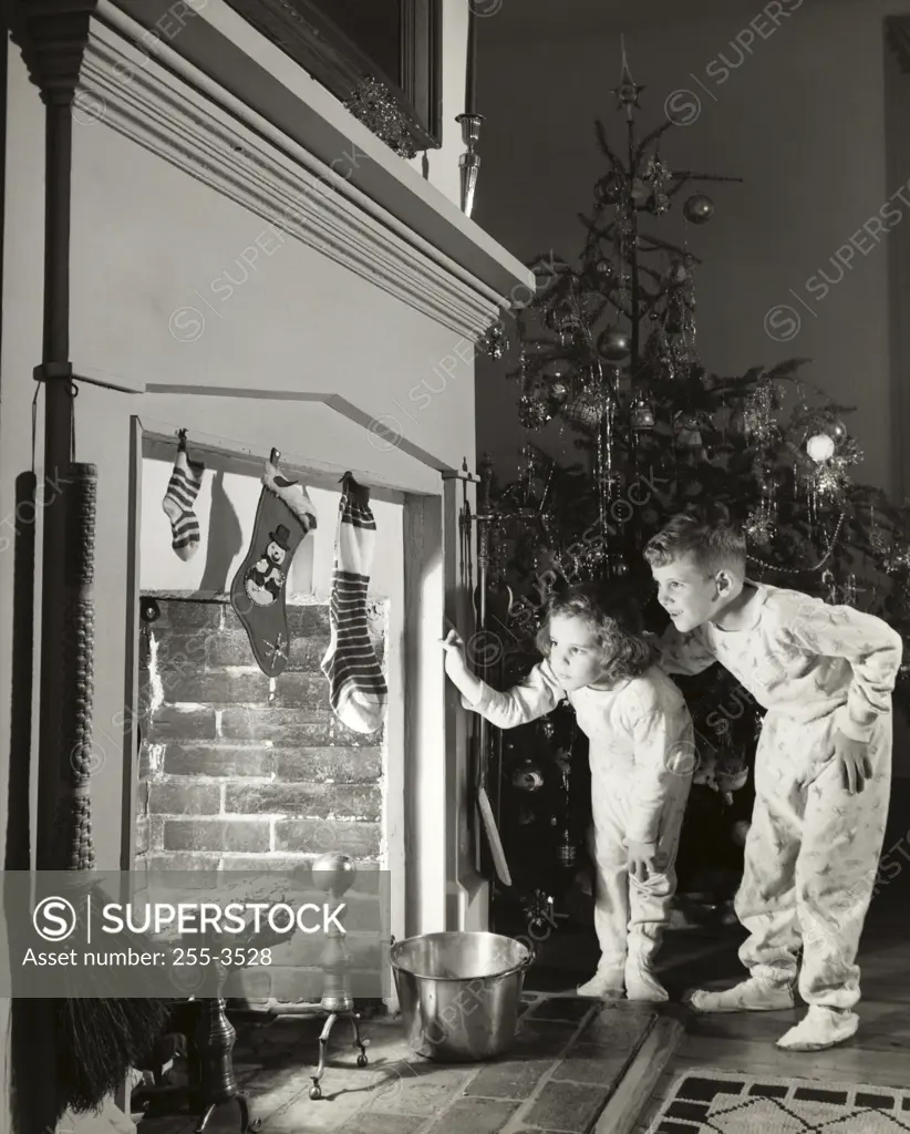 Boy and his sister peeking into a fireplace
