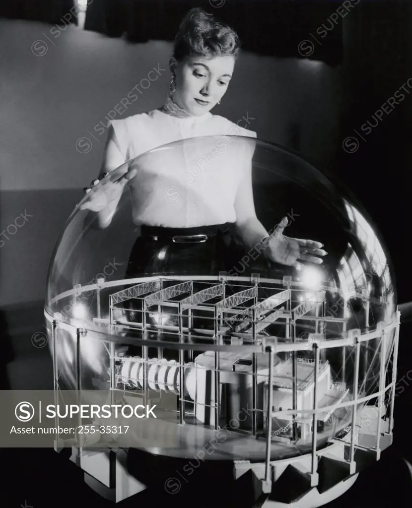 Young woman looking at a model of a nuclear reactor covered with sphere surrounding to protect against radioactivity, Knolls Atomic Power Laboratory, General Electric, Schenectady, New York, USA