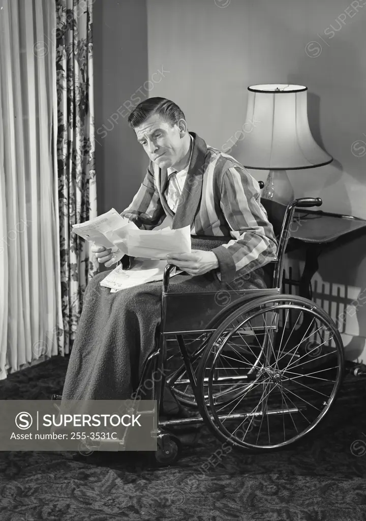 Vintage photograph. Man in wheelchair reading insurance forms.