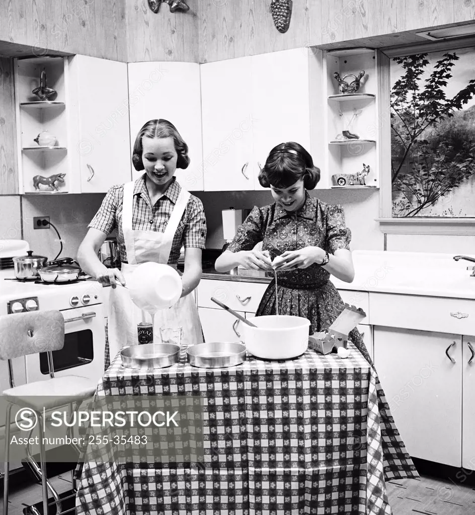 Two teenage girls preparing food in the kitchen