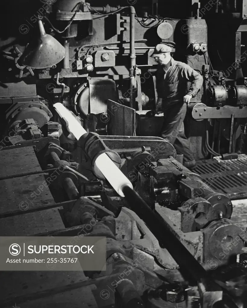 Vintage Photograph. Man watching machine piercing a seamless steel tube - Timken Steel and Tube Division
