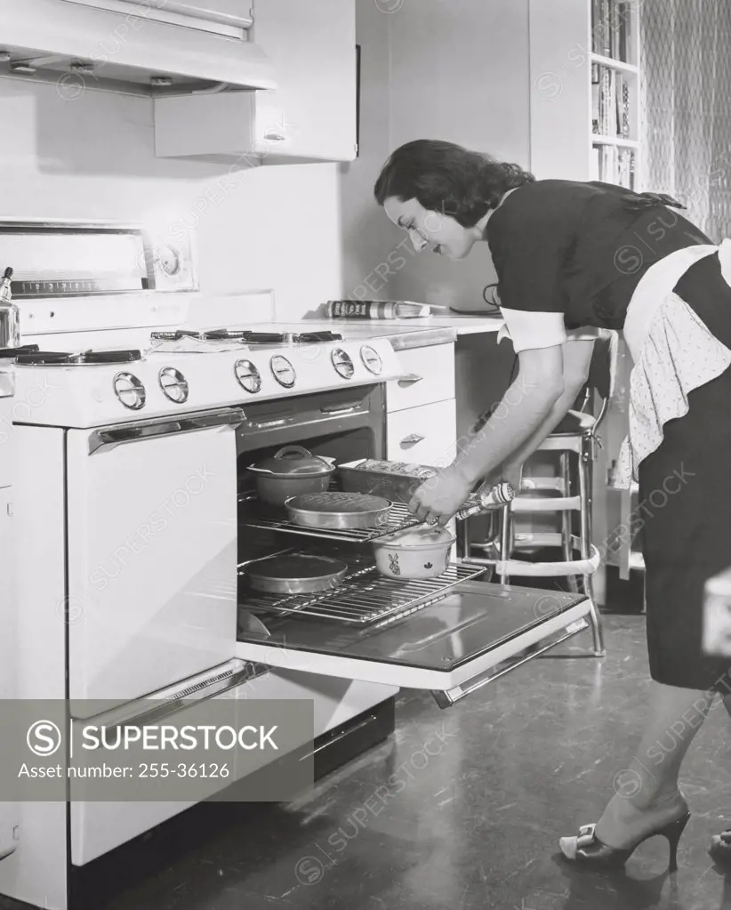 Mid adult woman putting food into an oven