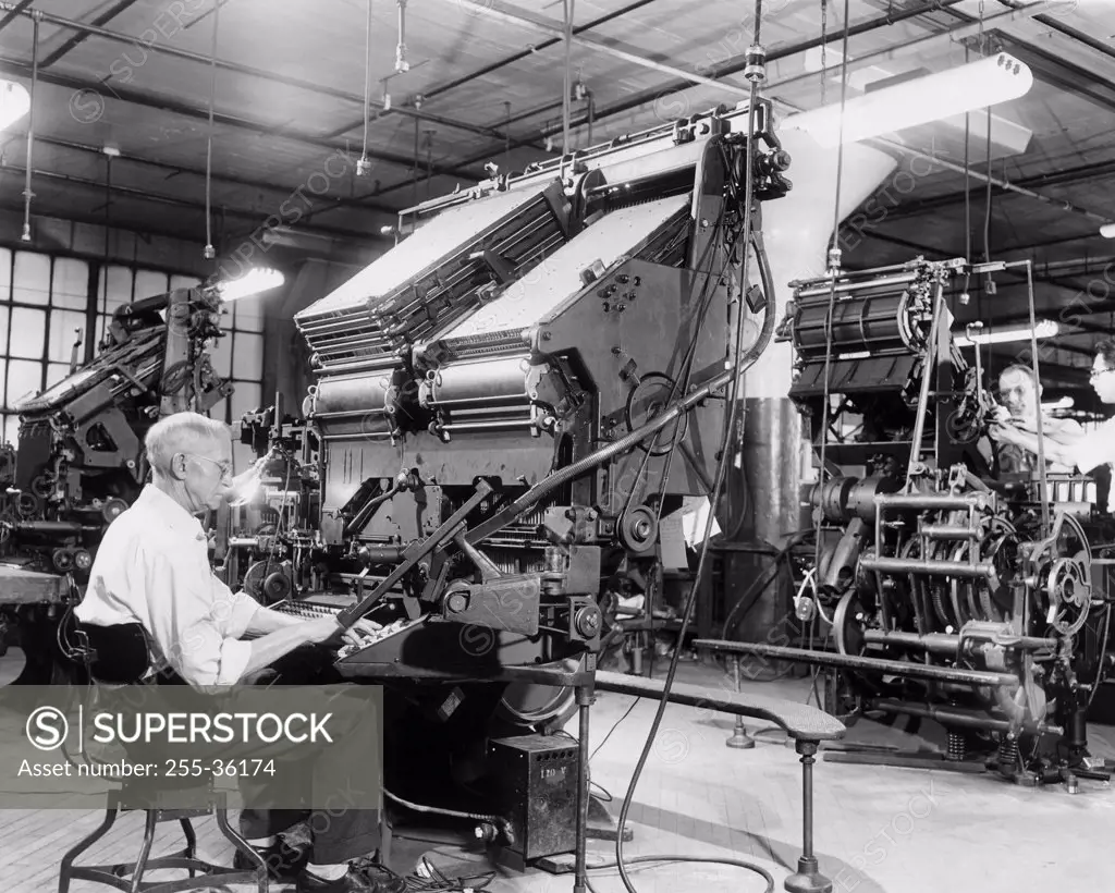 Three male workers operating linotype machines