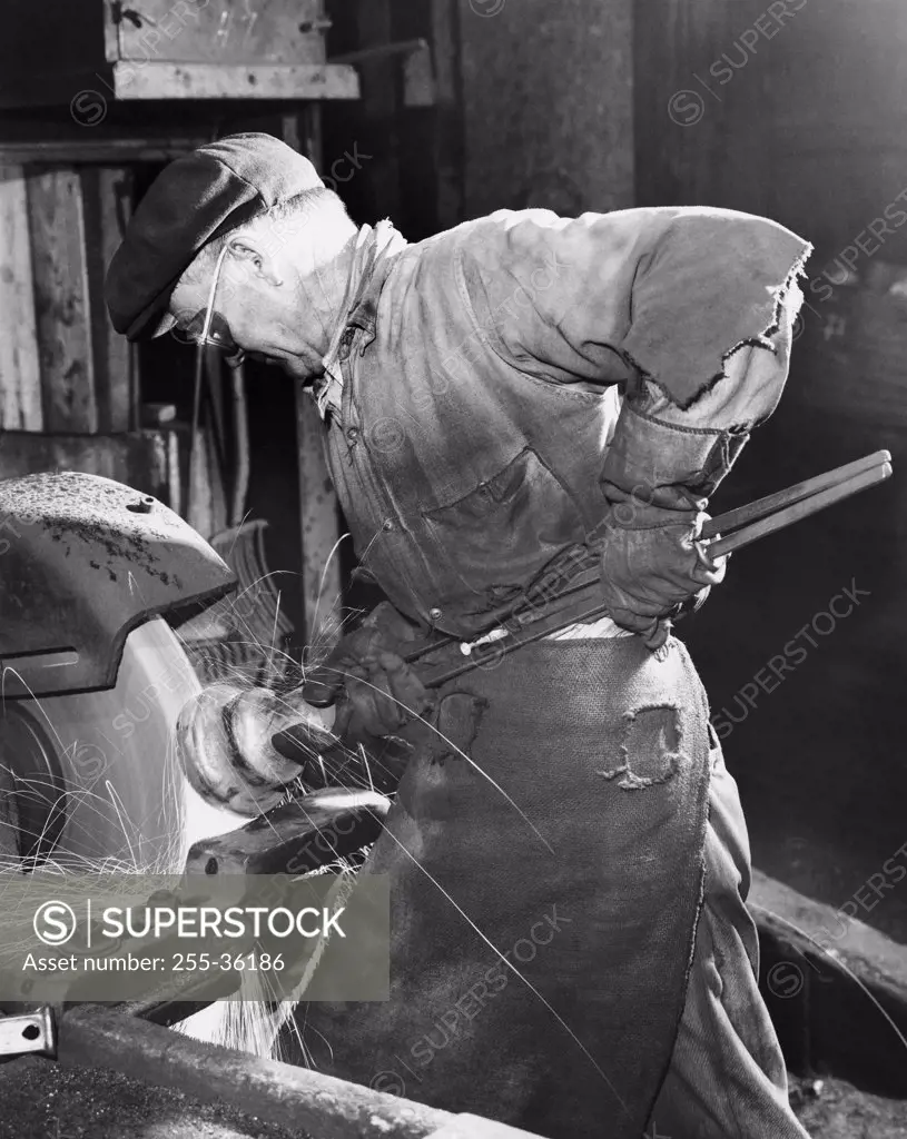 Side profile of a senior man working on a machine in a factory