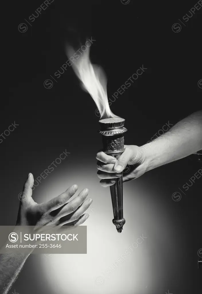 Vintage Photograph. Hand passing torch with flame to hand reaching up from bottom of frame with dark background, Frame 4