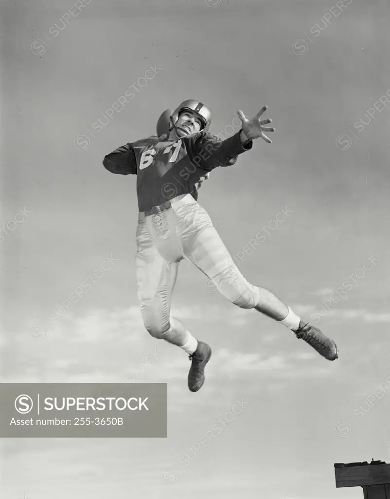 Vintage Photograph. Man in football uniform jumping in air about to throw football.