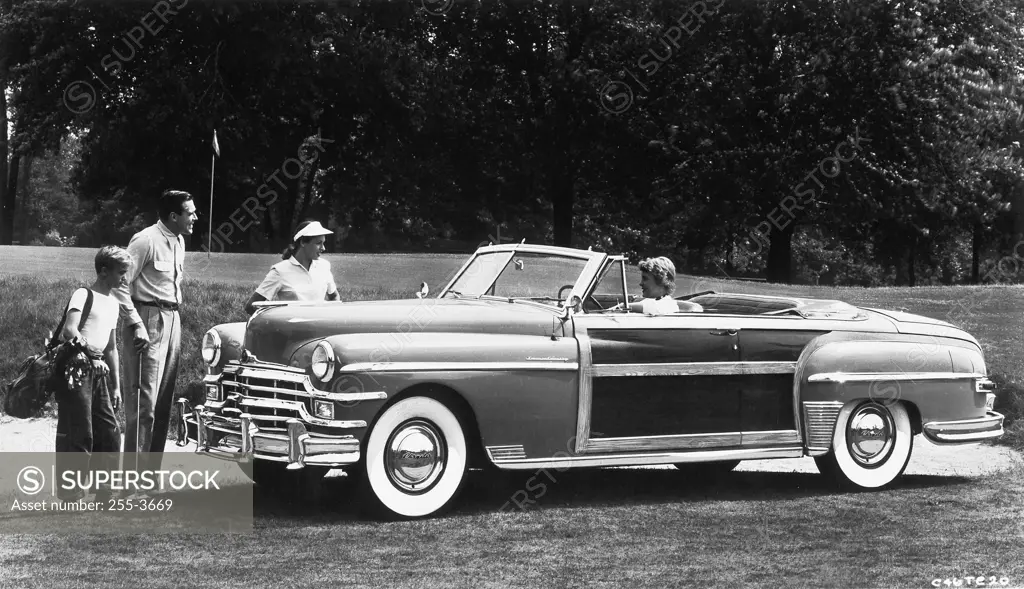 Father standing with his children and his wife sitting in a car, 1948 Chrysler Town and Country