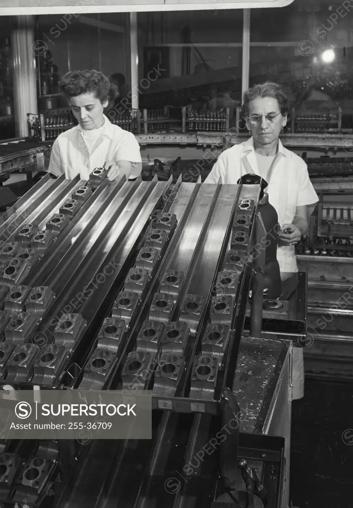 Vintage Photograph. Workers using air gauges to sort cylinders used in the household refrigerator compressor