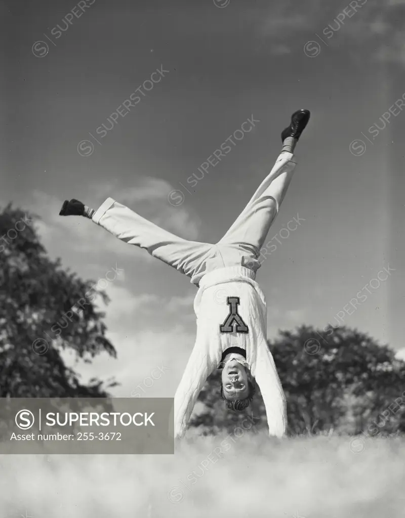 Vintage photograph. Man doing cartwheel in grass