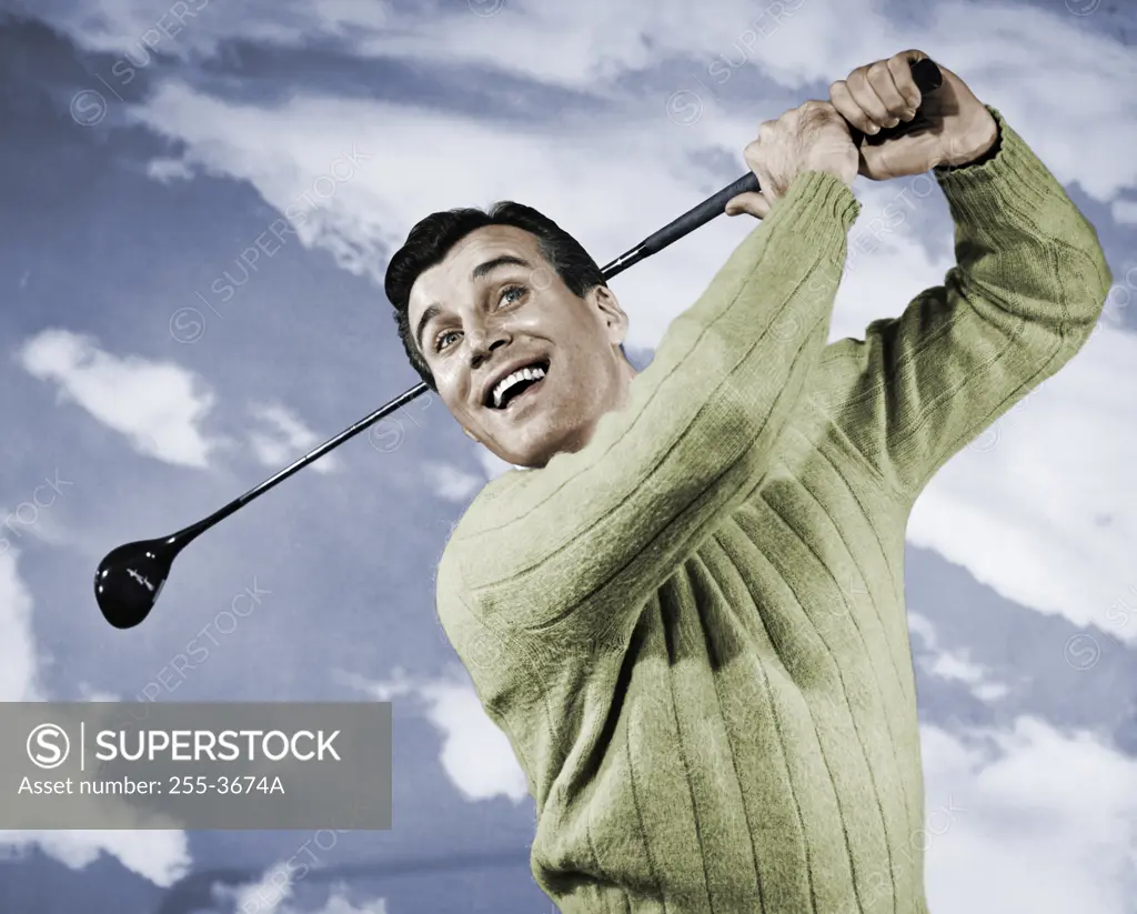 Vintage photograph. Close-up of mid adult man swinging golf club