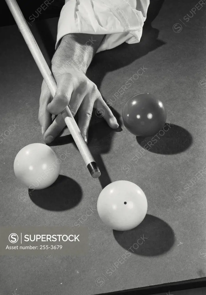 Vintage photograph. High angle view of a man's hand hitting a pool ball with a cue stick