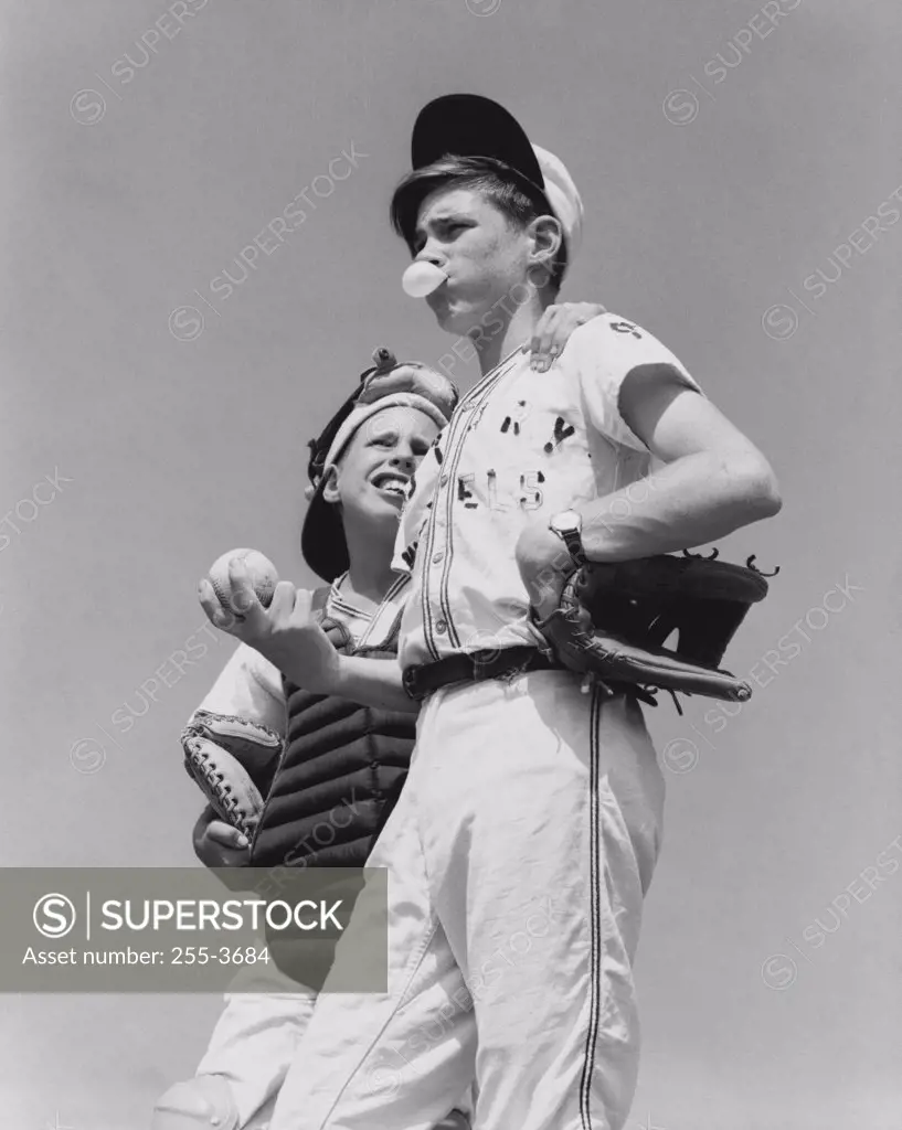 Low angle view of a youth league pitcher standing with a baseball catcher