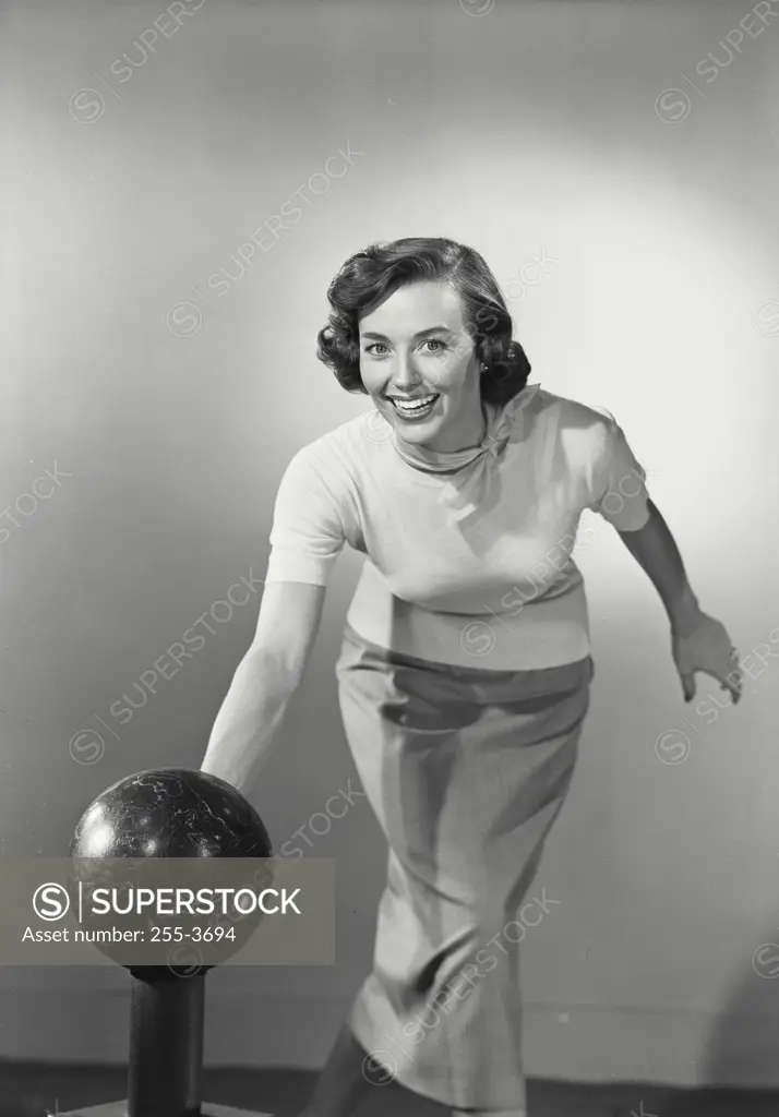 Vintage photograph. Young adult brunette woman smiling swinging bowling ball