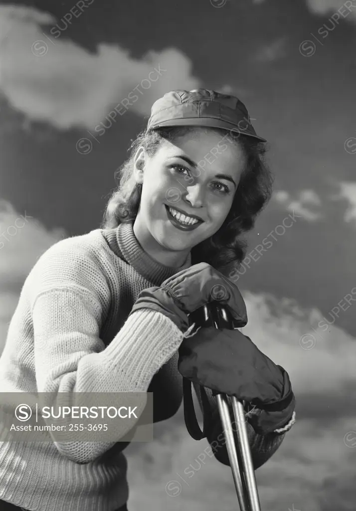 Vintage photograph. Woman in sweater and snow gloves leaning on ski poles.