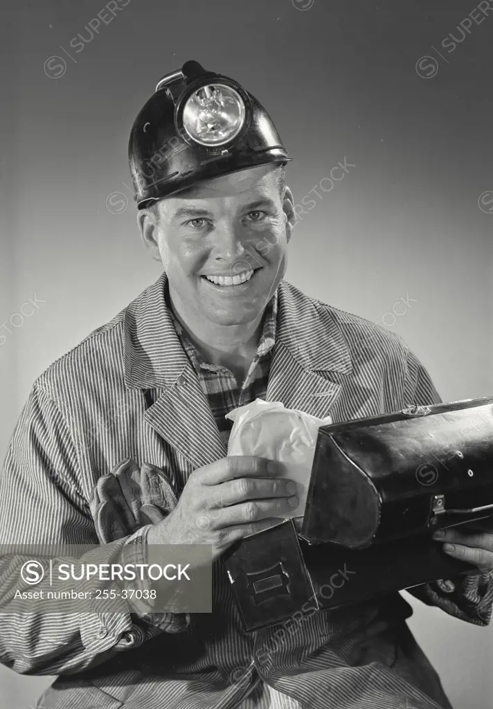 Working man in miners helmet with lunchbox and sandwich