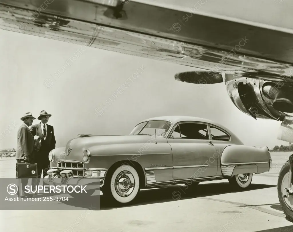 Two businessmen standing near a car, 1949 Cadillac Series 62 Club Coupe