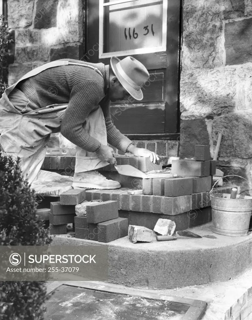 Side profile of a man laying bricks for a doorstep