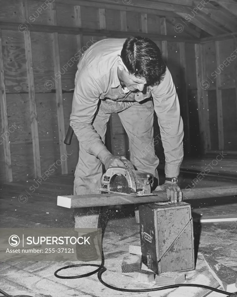 Carpenter sawing a wooden plank using an electric saw