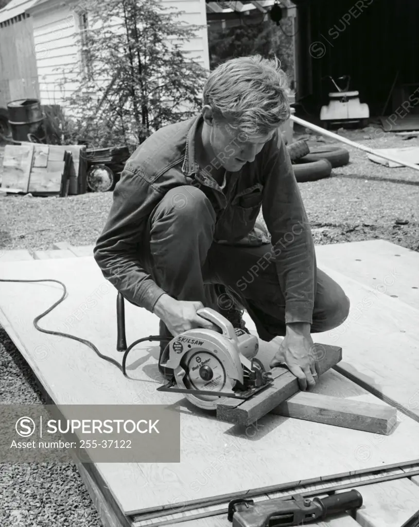 Carpenter sawing a wooden plank using an electric saw
