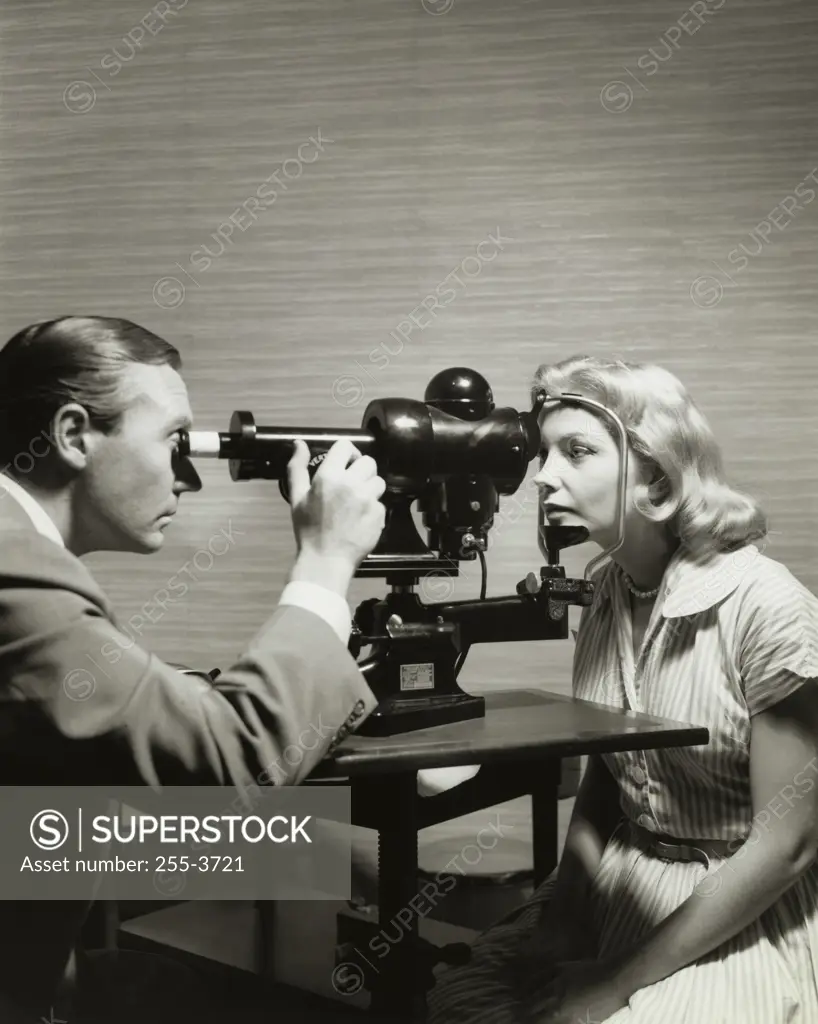 Side profile of an optometrist examining eyes of a patient