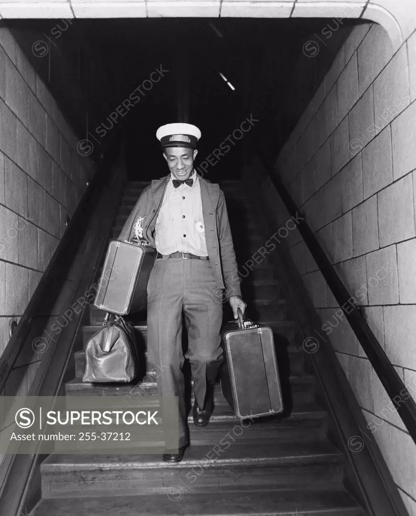 Mid adult man moving down a staircase with luggage