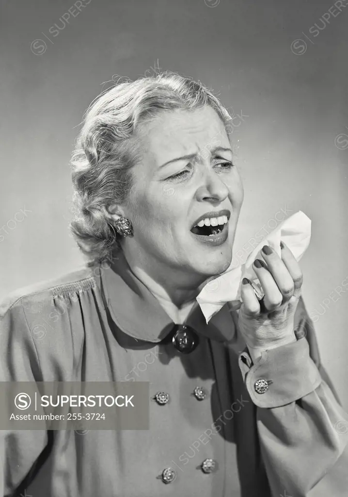 Vintage photograph. Woman in button coat sneezing into handkerchief