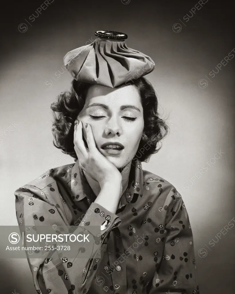 Close-up of a young woman with an ice pack on her head suffering from a headache