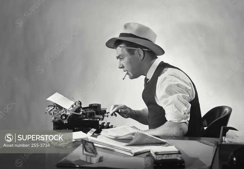 Vintage Photograph. Side profile of a journalist typing on a typewriter