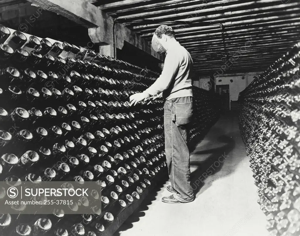 Vintage photograph. Manual worker working in a storage room riddling bottles of champagne