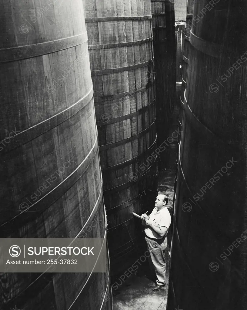 Vintage photograph. High angle view of a male worker standing in a storage room of a winery at Guasti California
