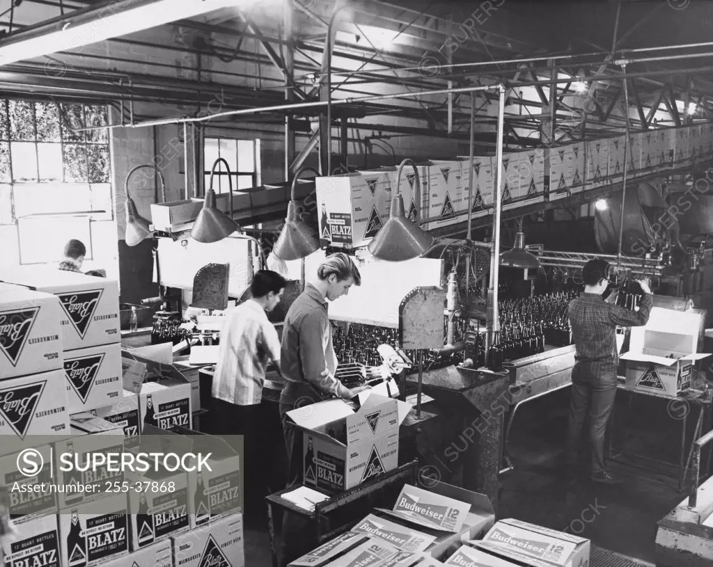 High angle view of three male workers working in a glass bottle manufacturing plant