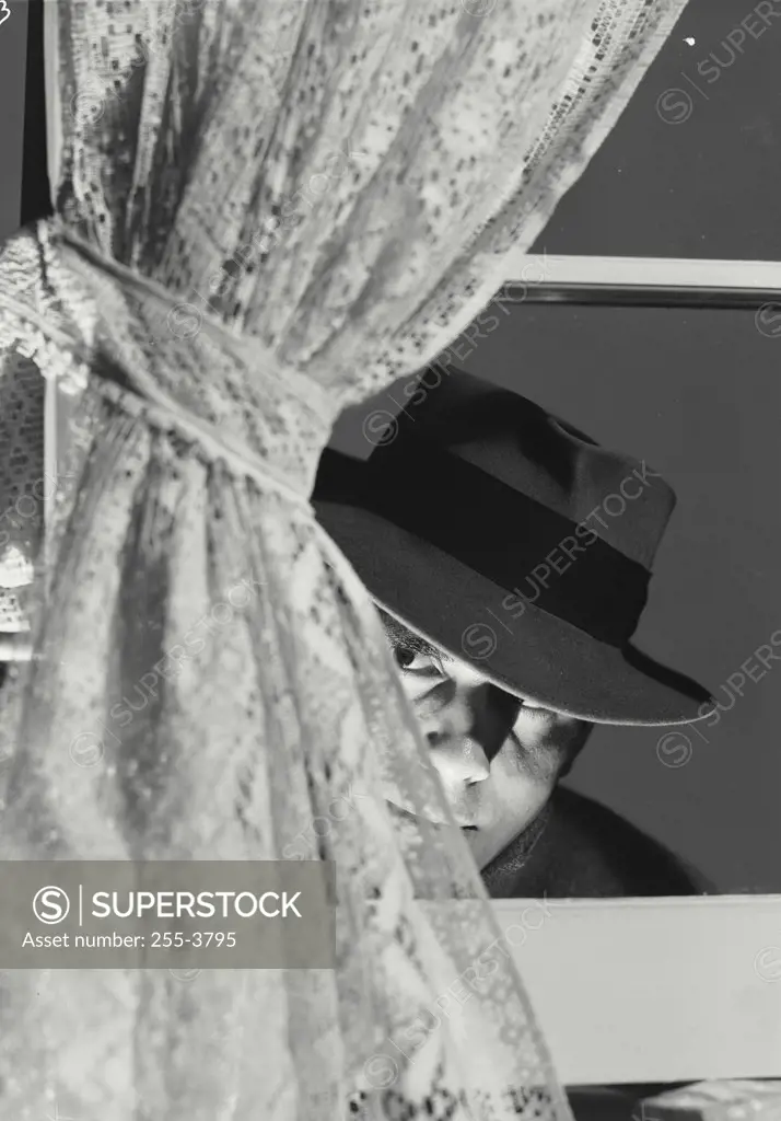 Vintage photograph. Suspicious man peering through window. 