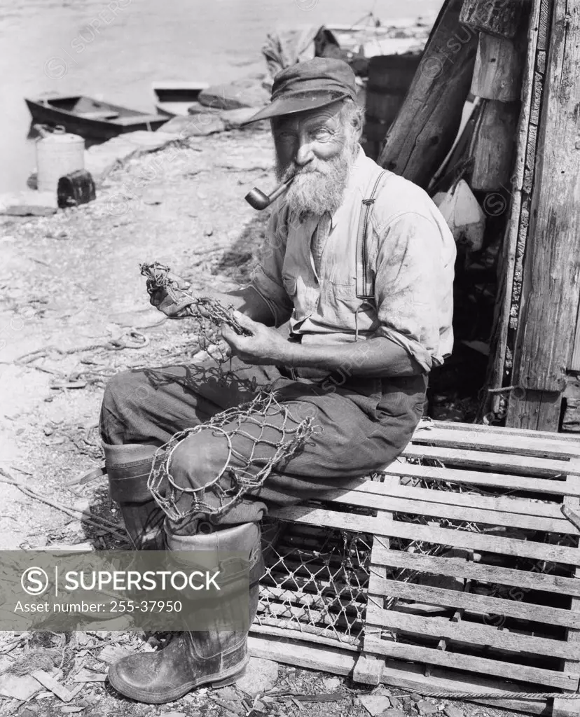 Portrait of a fisherman sitting on a lobster trap and holding a fishing net
