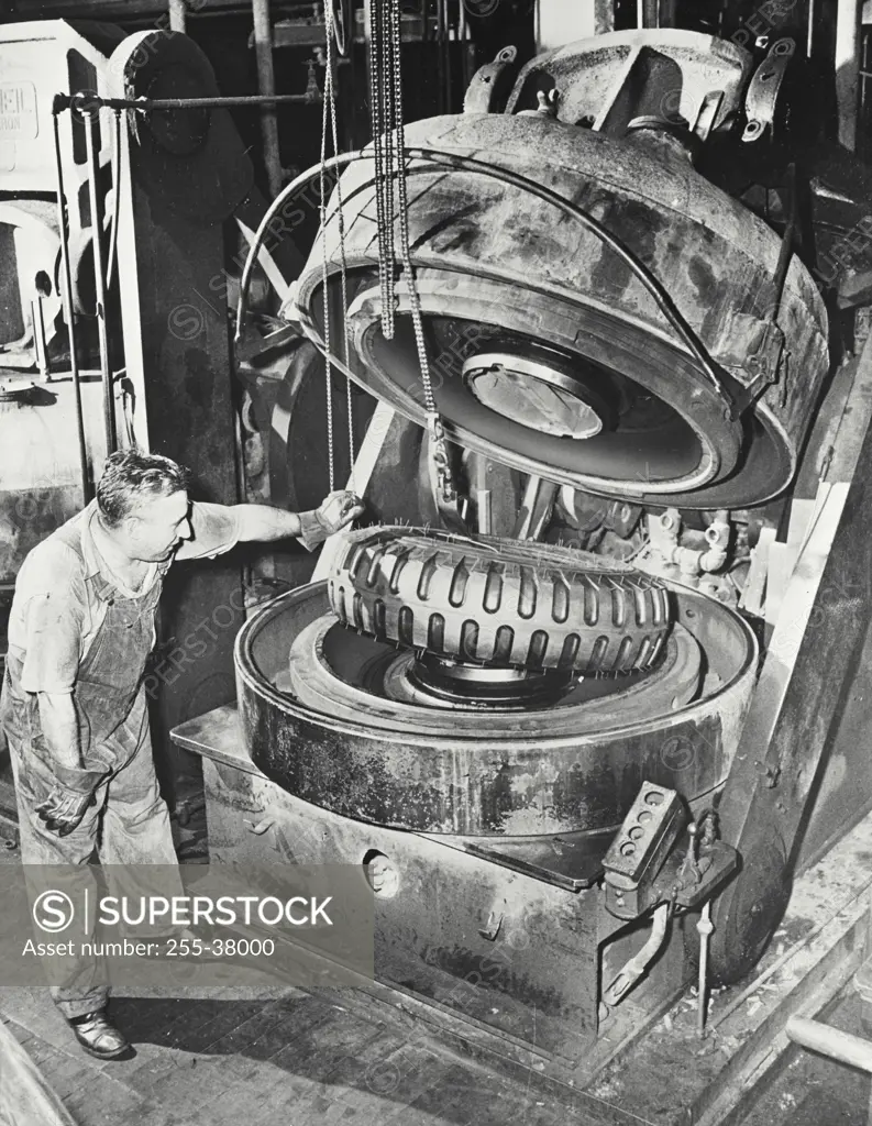 Vintage photograph. Removing a cured truck tire from its mold in a United States Rubber Company factory