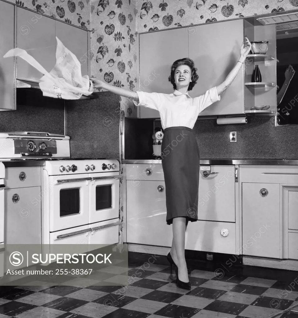 Young woman in kitchen tossing apron in air