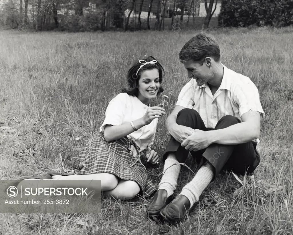 Young couple sitting in a park smiling