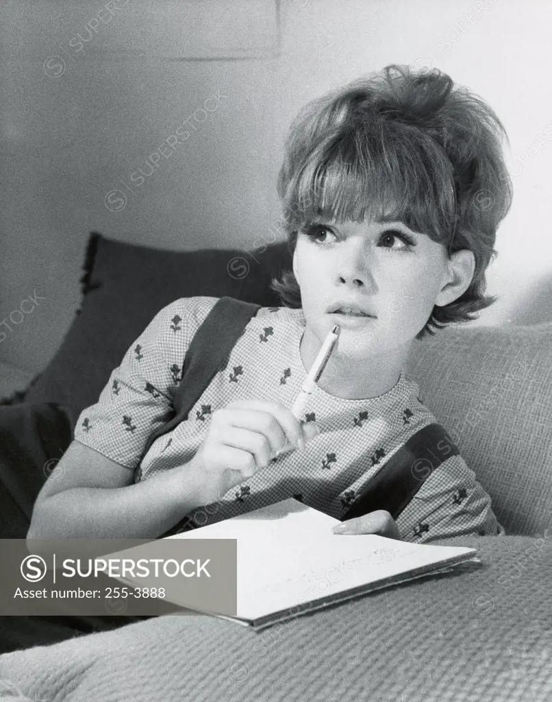Close-up of a teenage girl holding a pen and a book
