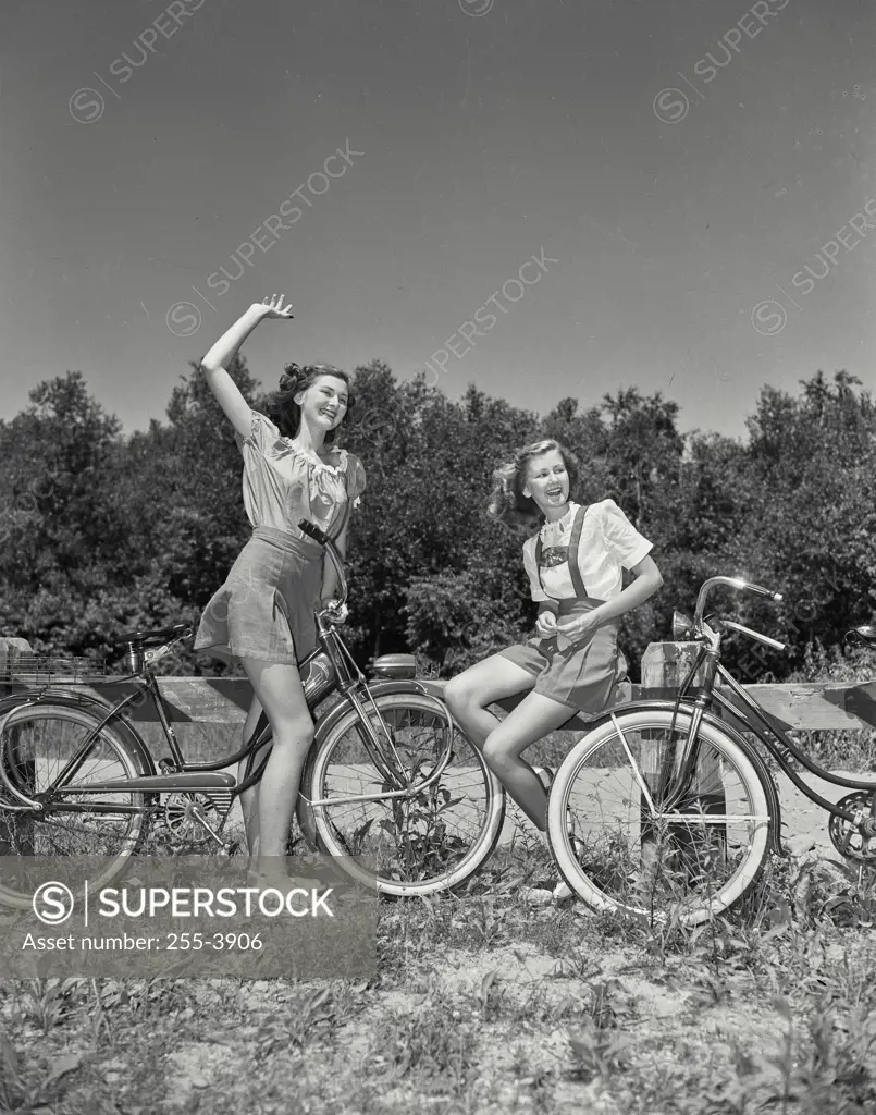Vintage Photograph. Girls sitting on bicycles in field together waving