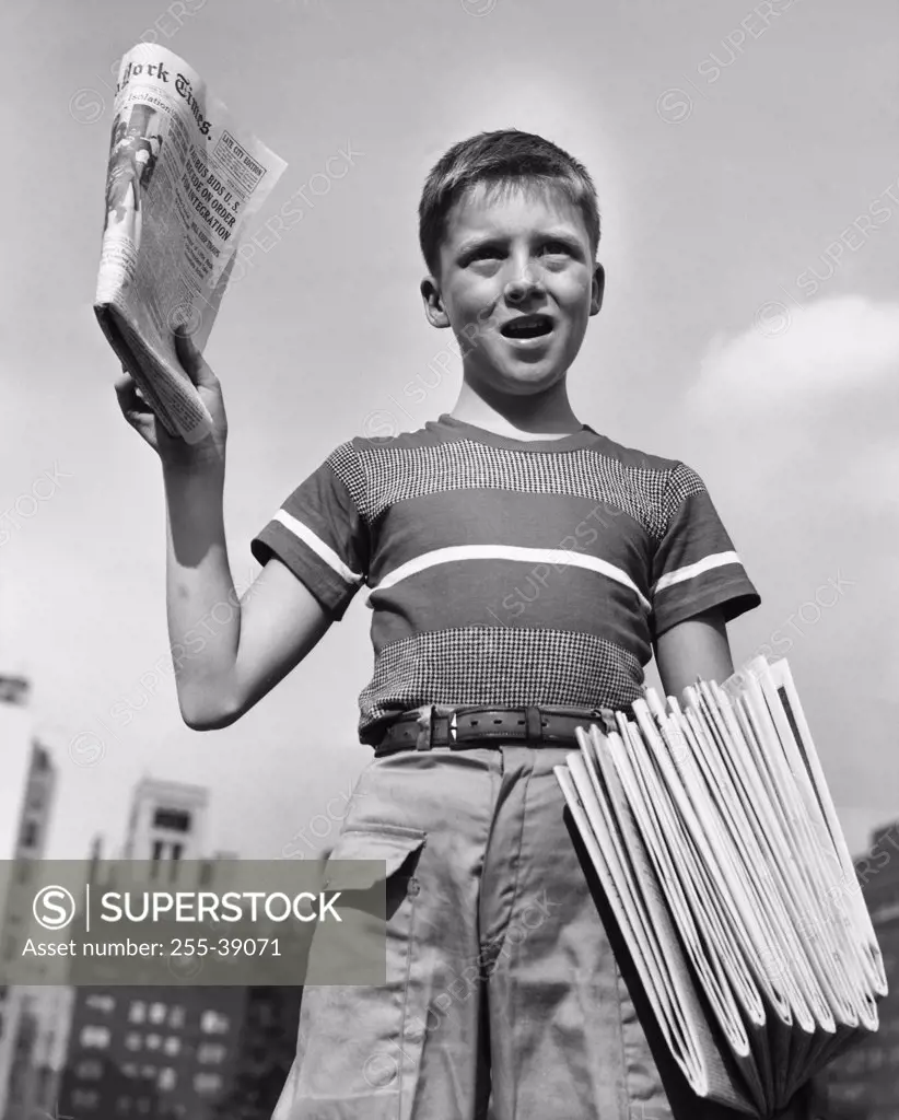 Low angle view of a boy selling newspapers