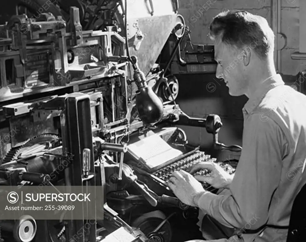 Side profile of a male worker operating a linotype machine