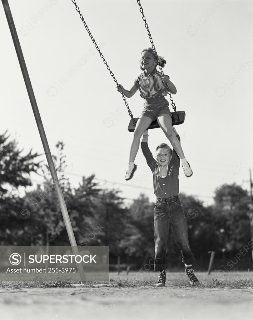 Vintage Photograph. Young boy pushing girl on swing. Frame 2
